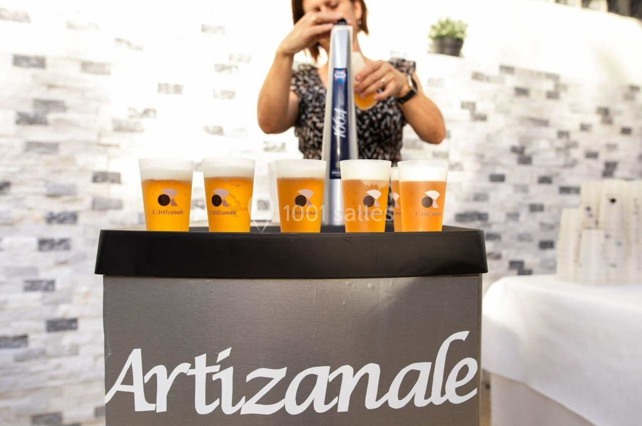 Une personne sert des bières artisanales dans des verres alignés sur un comptoir extérieur.