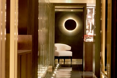 Couloir élégant avec éclairage tamisé, sol brillant et décoration murale en forme de soleil lumineux au fond.