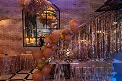 Salle décorée pour une fête avec des tables garnies, une boule disco et des ballons formant le chiffre 40.