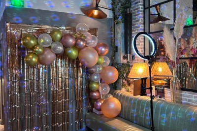Salle décorée pour une fête avec des tables garnies, une boule disco et des ballons formant le chiffre 40.
