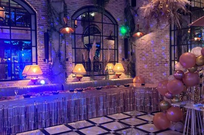 Salle décorée pour une fête avec des tables garnies, une boule disco et des ballons formant le chiffre 40.