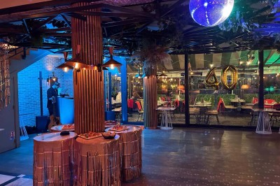 Salle décorée pour une fête avec des tables garnies, une boule disco et des ballons formant le chiffre 40.