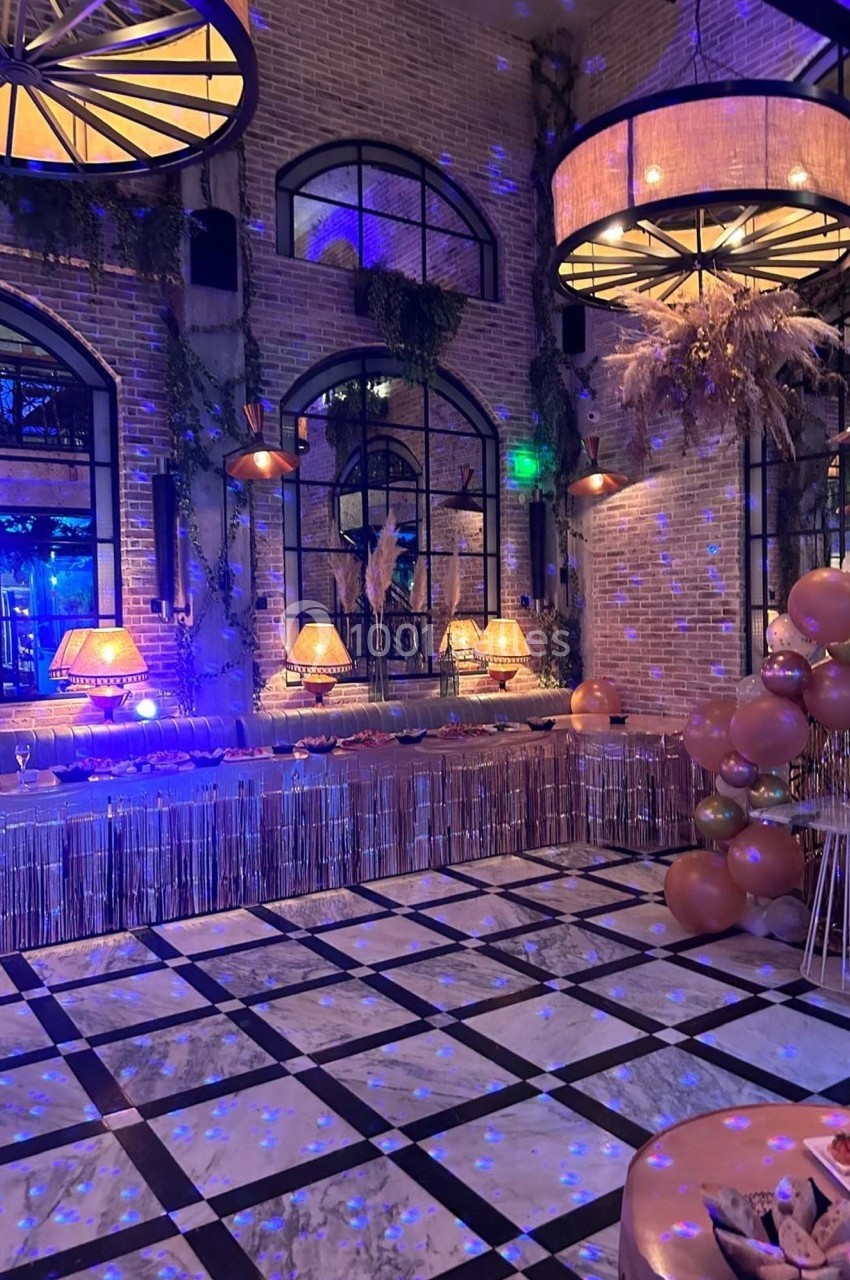 Salle décorée pour un événement avec guirlandes, ballons, lampes chaleureuses et ambiance lumineuse festive.