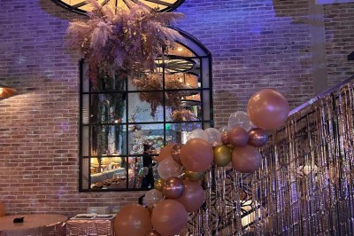 Salle décorée pour une fête avec tables, guirlandes, ballon ’40’ doré et éclairage coloré.
