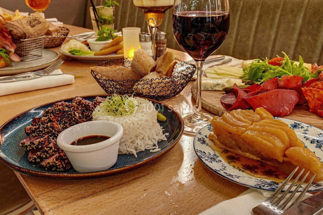 Repas composé de thon en croûte de sésame, riz, charcuterie, salade, pain, tarte aux fruits et verre de vin rouge.