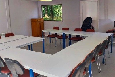 Chambre avec deux lits superposés en bois, fenêtres avec stores bleus et murs blancs.