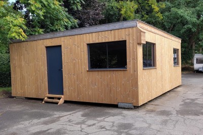 Chambre avec deux lits superposés en bois, fenêtres avec stores bleus et murs blancs.