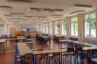 Chambre avec deux lits superposés en bois, fenêtres avec stores bleus et murs blancs.