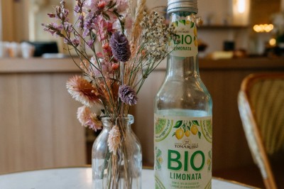 Façade d'un salon de thé parisien avec une devanture noire, une enseigne beige et des chaises en terrasse.