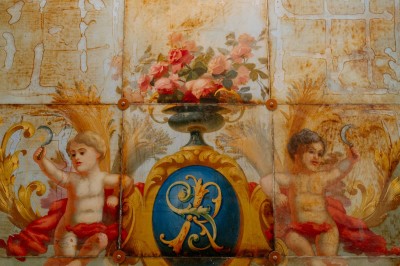 Façade d'un salon de thé parisien avec une devanture noire, une enseigne beige et des chaises en terrasse.