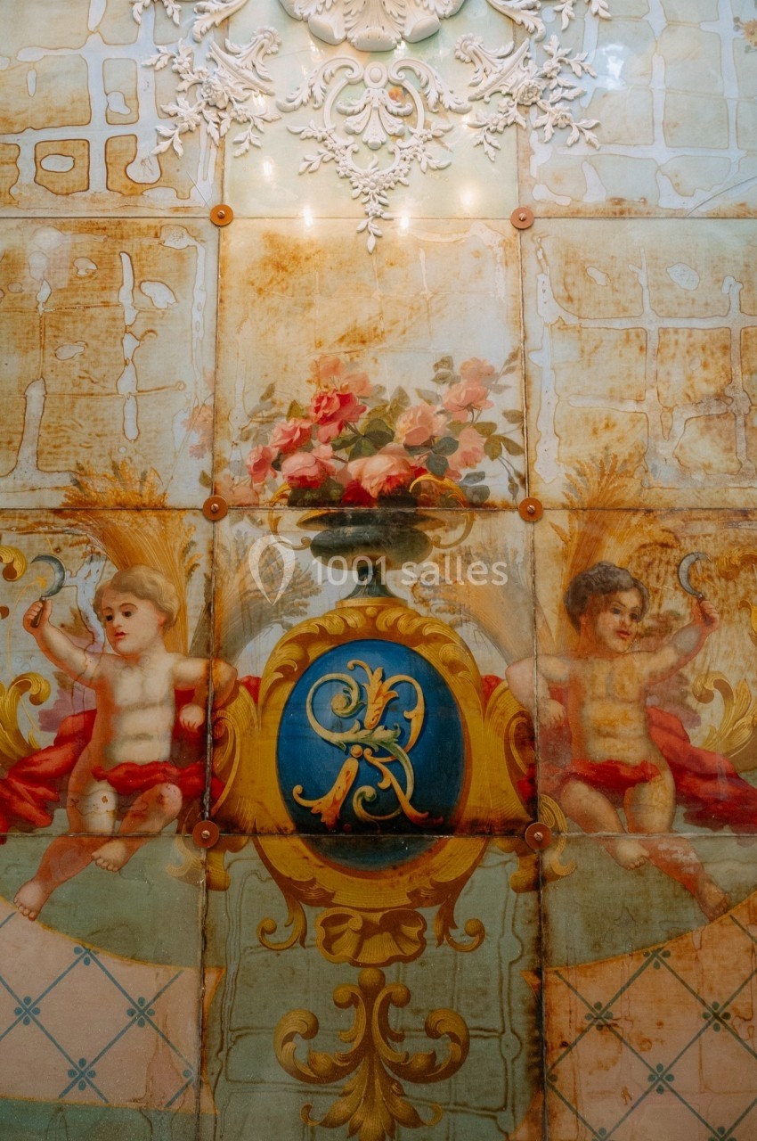 Peinture murale décorative avec deux chérubins, un vase de fleurs et des motifs dorés sur un fond vieilli.