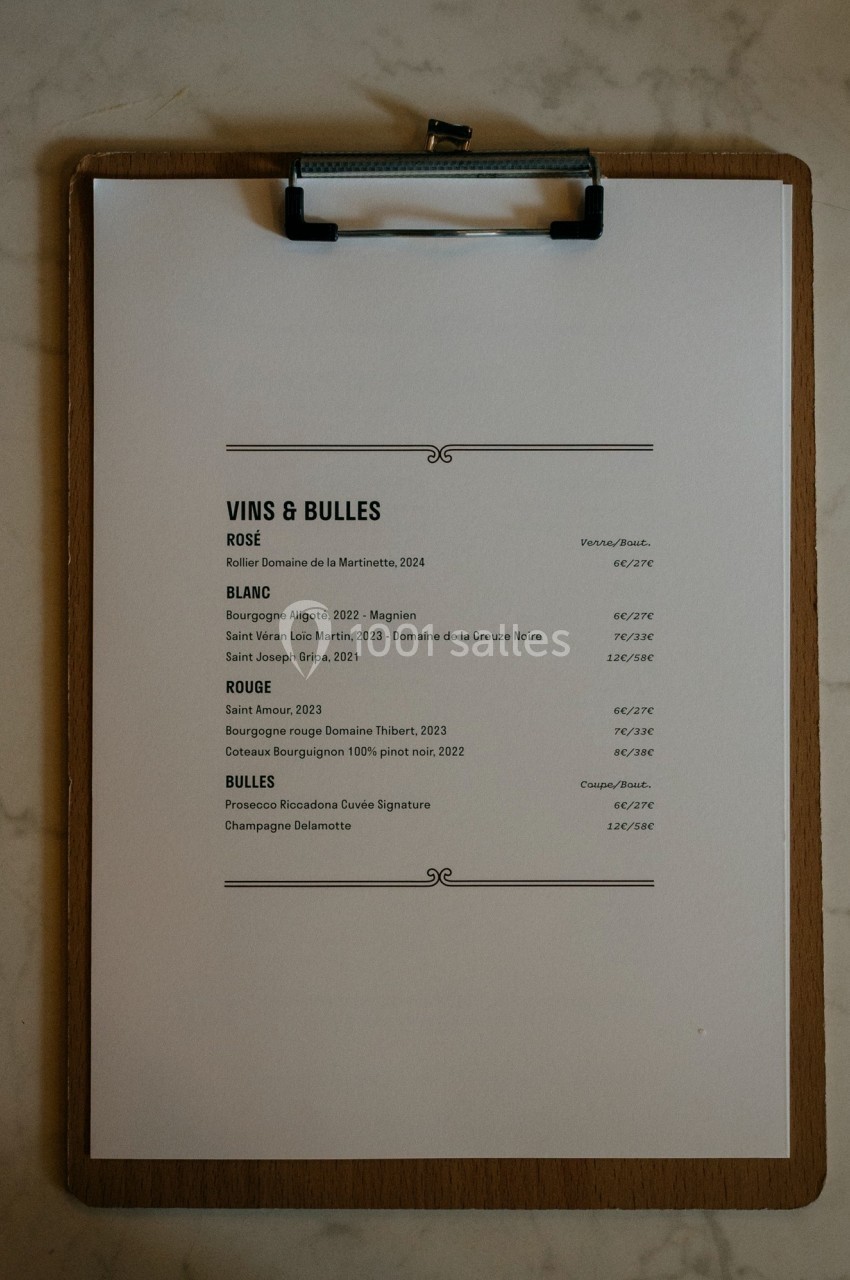 Carte des vins et bulles imprimée sur une feuille blanche fixée à une planchette en bois, posée sur une surface en marbre.