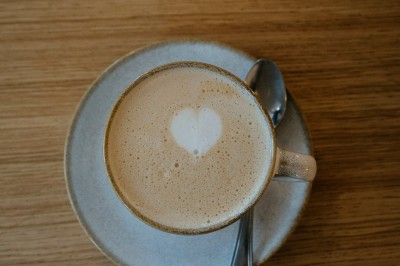 Façade d'un salon de thé parisien avec une devanture noire, une enseigne beige et des chaises en terrasse.
