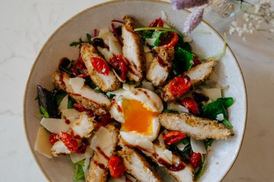 Façade d'un salon de thé parisien avec une devanture noire, une enseigne beige et des chaises en terrasse.