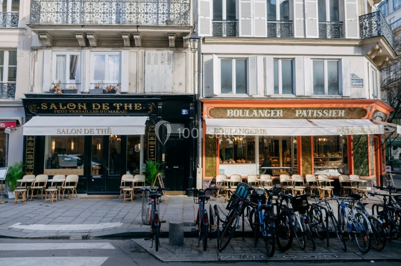 Façades d'un salon de thé et d'une boulangerie-pâtisserie avec des vélos stationnés devant sur un trottoir parisien.