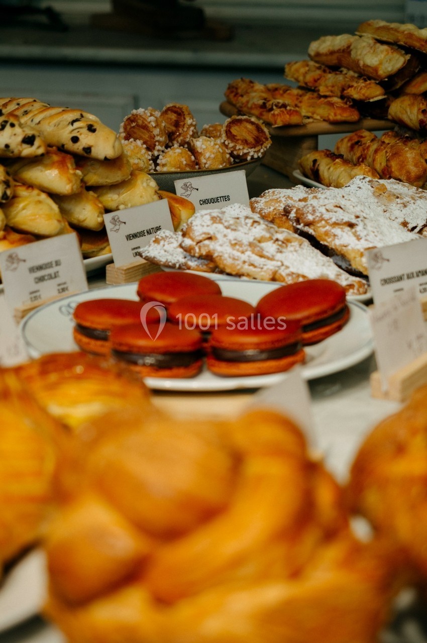 Assortiment de viennoiseries et pâtisseries variées présentées sur un comptoir, dont macarons et croissants.