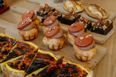 Façade d'un salon de thé parisien avec une devanture noire, une enseigne beige et des chaises en terrasse.