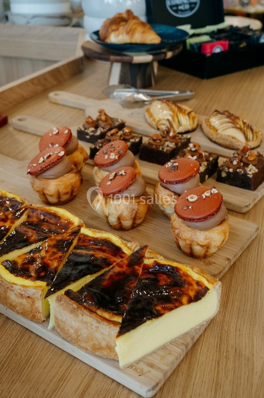 Assortiment de pâtisseries sur une table en bois, incluant flans, viennoiseries et gâteaux décorés.