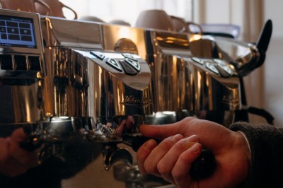 Façade d'un salon de thé parisien avec une devanture noire, une enseigne beige et des chaises en terrasse.
