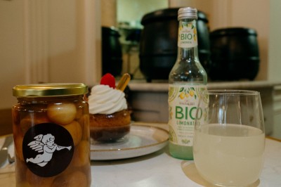 Façade d'un salon de thé parisien avec une devanture noire, une enseigne beige et des chaises en terrasse.