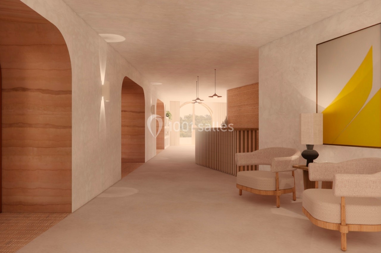 Couloir lumineux avec murs en terre cuite, fauteuils en bois clair, lampe et tableau abstrait aux tons jaunes.