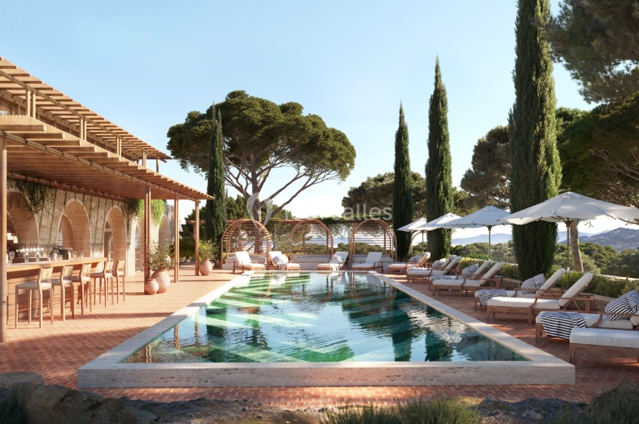 Piscine extérieure entourée de chaises longues, parasols, pergola en bois et végétation méditerranéenne.