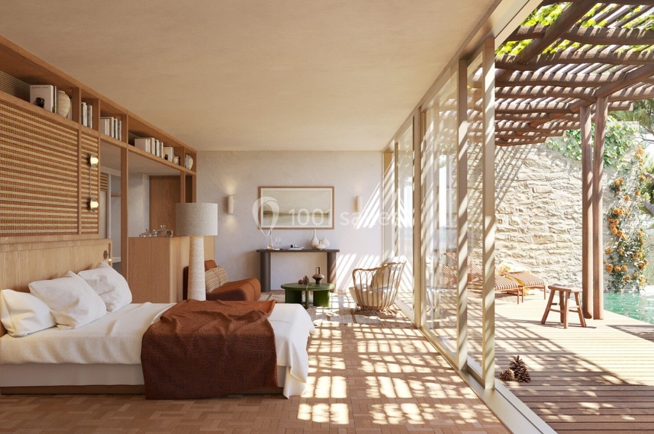 Chambre lumineuse avec lit double, mobilier en bois, grande baie vitrée et terrasse donnant sur un jardin verdoyant.