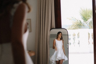 Femme buvant un cocktail rouge avec une paille, en extérieur, cheveux blonds au vent.