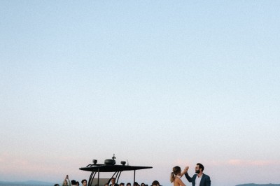 Femme buvant un cocktail rouge avec une paille, en extérieur, cheveux blonds au vent.