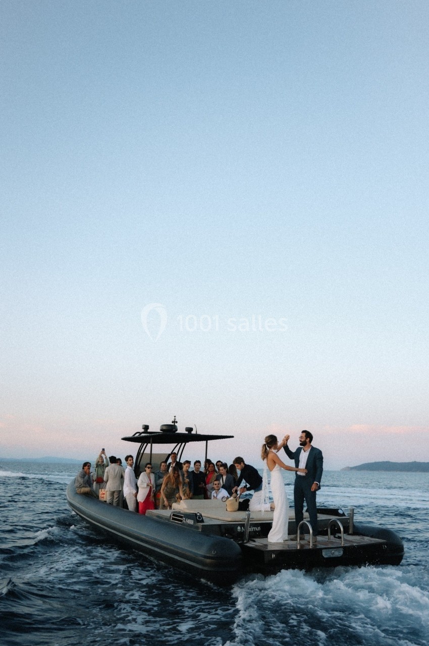 Un groupe de personnes sur un bateau pneumatique naviguant sur une mer calme au coucher du soleil.