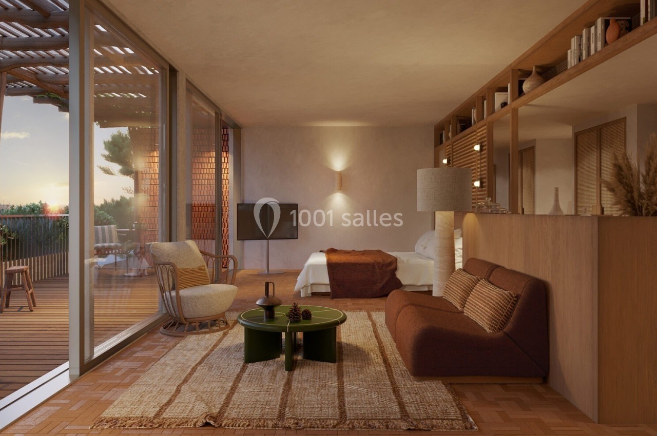 Salon chaleureux avec mobilier en bois, canapé brun, table basse verte, et vue sur une terrasse au coucher du soleil.