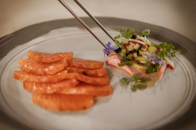 Femme buvant un cocktail rouge avec une paille, en extérieur, cheveux blonds au vent.