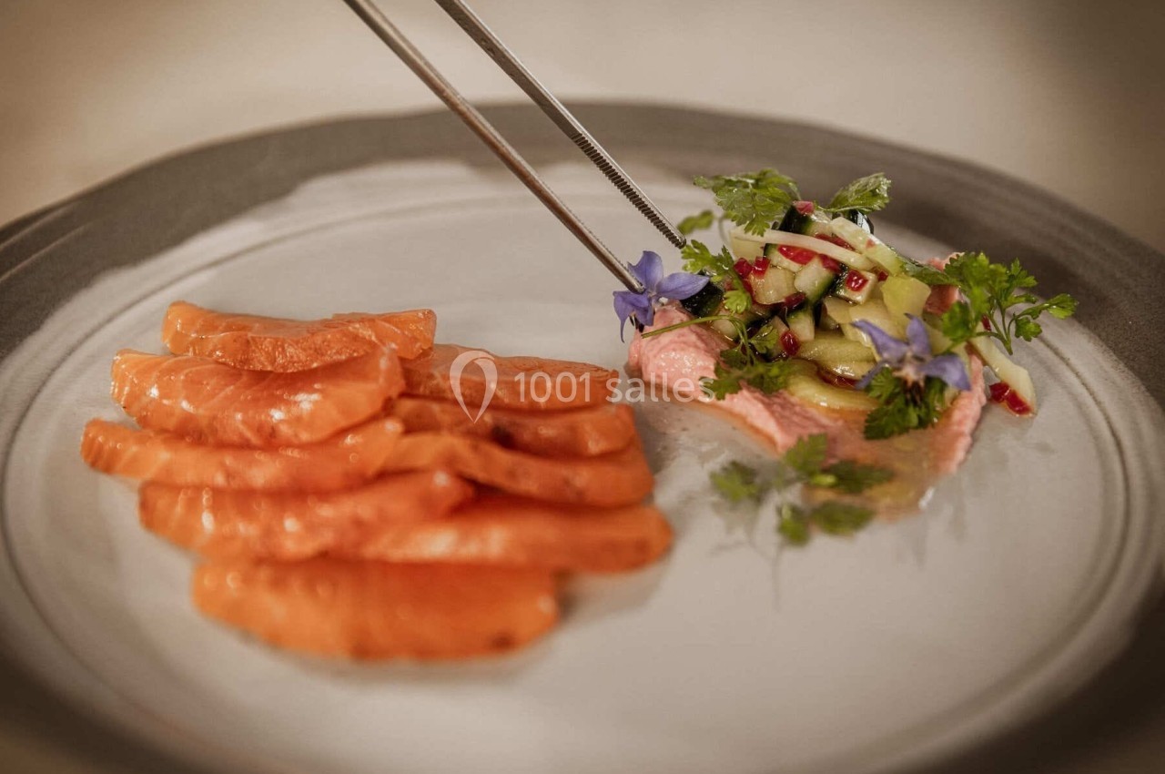 Tranches de saumon cru accompagnées d'une garniture de légumes, herbes fraîches et fleurs comestibles.