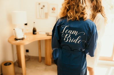 Femme buvant un cocktail rouge avec une paille, en extérieur, cheveux blonds au vent.