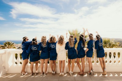Femme buvant un cocktail rouge avec une paille, en extérieur, cheveux blonds au vent.