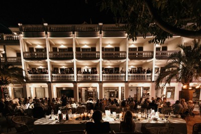 Femme buvant un cocktail rouge avec une paille, en extérieur, cheveux blonds au vent.