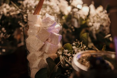 Femme buvant un cocktail rouge avec une paille, en extérieur, cheveux blonds au vent.