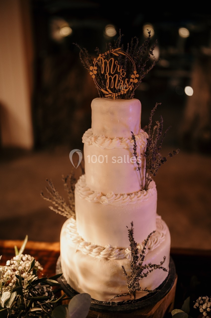 Gâteau de mariage à trois étages décoré de fleurs séchées et d'un topper ’Mr & Mrs’ doré.