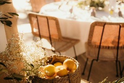 Femme buvant un cocktail rouge avec une paille, en extérieur, cheveux blonds au vent.