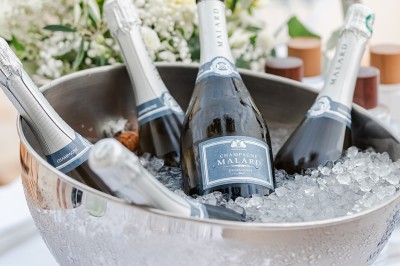 Femme buvant un cocktail rouge avec une paille, en extérieur, cheveux blonds au vent.