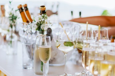 Femme buvant un cocktail rouge avec une paille, en extérieur, cheveux blonds au vent.