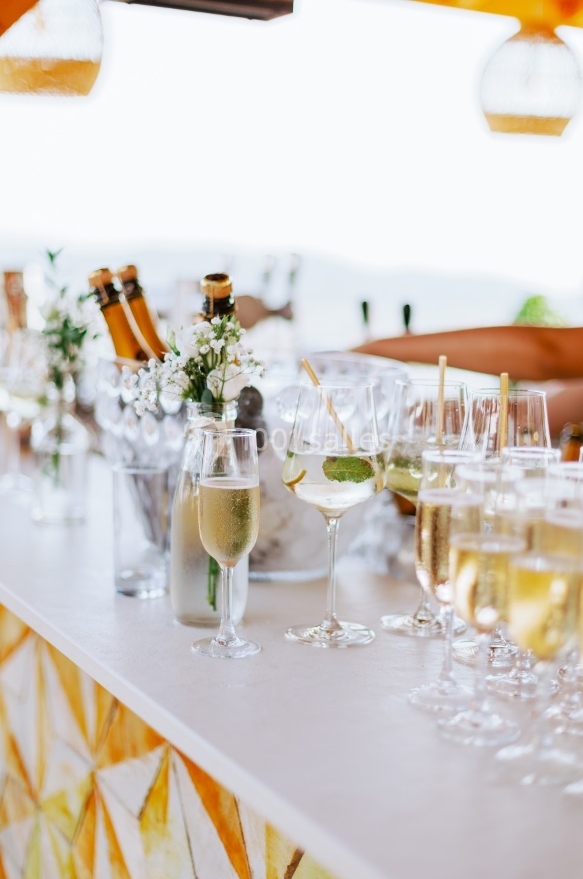 Bar extérieur avec des verres de champagne, cocktails garnis de menthe et bouteilles dans un seau à glace.