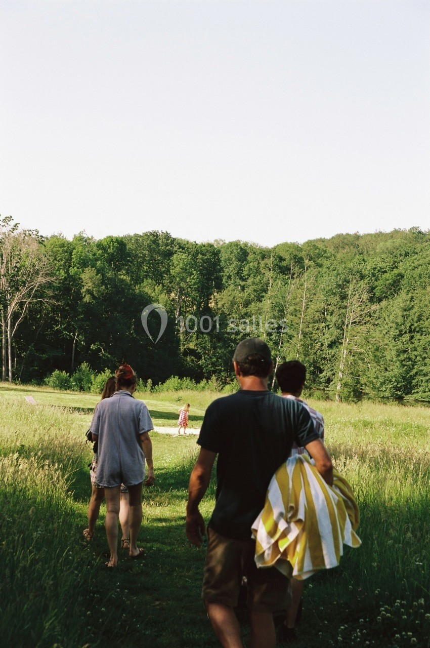 Un groupe de personnes marche sur un sentier herbeux entouré de nature verdoyante par une journée ensoleillée.