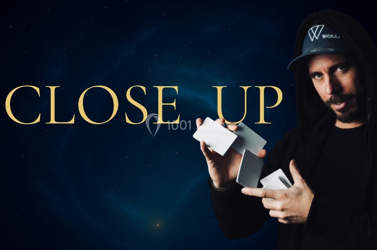 Un homme en tenue sombre manipule des cartes blanches devant un fond étoilé avec le texte ’CLOSE UP’.