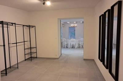 Abri en bois avec toit en pente, sol en gravier et clôture adjacente, situé dans un environnement arboré.