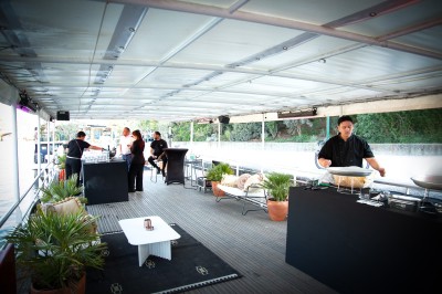Miniature Location salle Paris 5 (Paris) - Péniche Amour #2 Terrasse d'un bateau aménagée avec des tables et des sièges, vue sur la tour Eiffel et un pont au coucher du soleil.