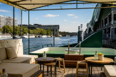 Miniature Location salle Paris 5 (Paris) - Péniche Amour #9 Terrasse aménagée sur une péniche avec vue sur la Seine, des bâtiments et un pont en arrière-plan.