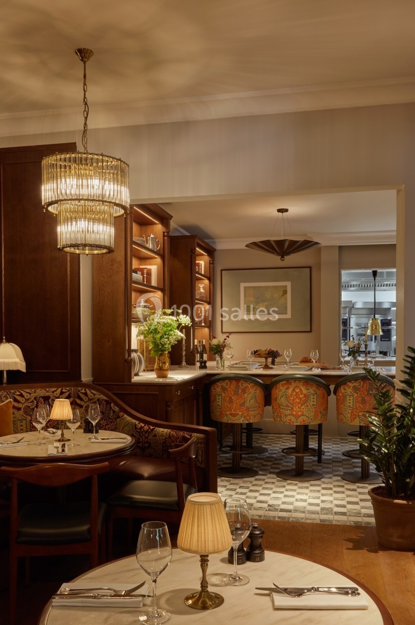 Salle de restaurant élégante avec tables dressées, bar en arrière-plan et éclairage chaleureux.