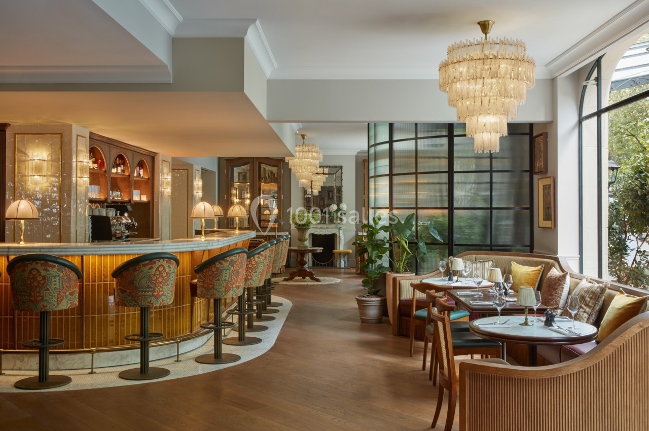 Intérieur d'un restaurant élégant avec un bar en bois, des lustres en cristal et des tables dressées près de grandes…