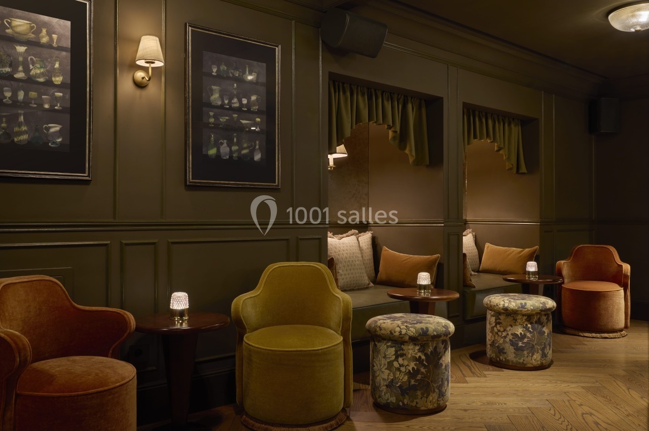 Espace lounge avec fauteuils, poufs et tables basses, éclairé par des appliques murales dans une ambiance feutrée.